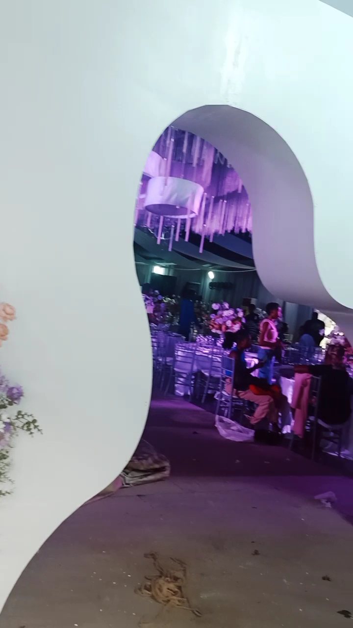 Curved white arch opening onto a purple-lit hall