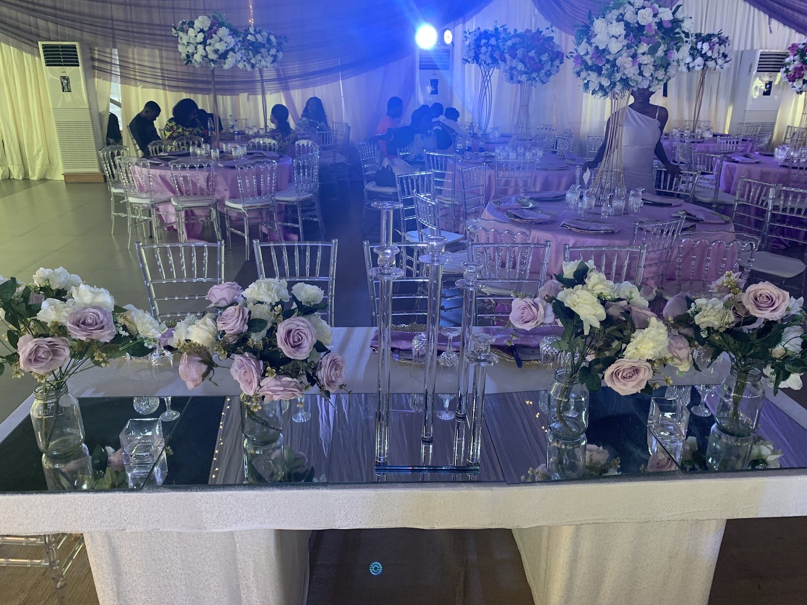 Tables set with lilac florals and mirrored centrepieces under blue lighting