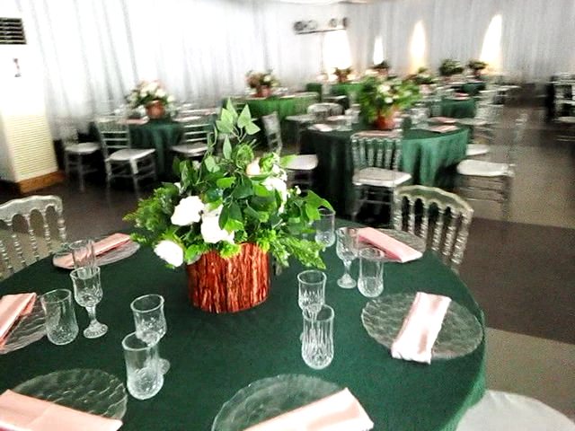 Round tables with emerald linen, pink napkins, glass plates and a white floral centrepiece